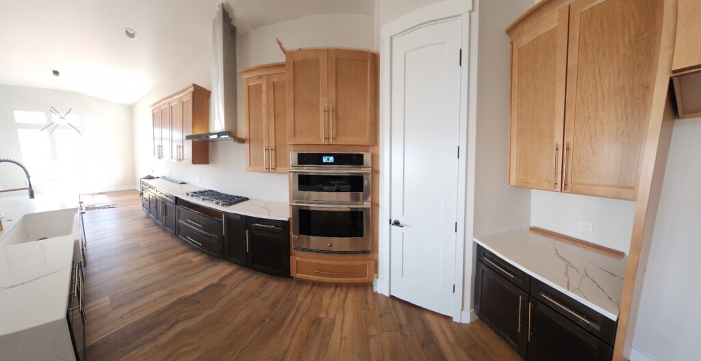 Kitchen remodel with light wood upper cabinets, dark lower cabinetry, and stainless steel appliances